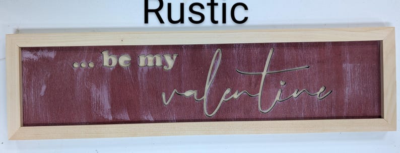 Handmade cypress frame with Baltic birch. The background is burgandy with white brush strokes. The natural Baltic birch letters read ...be my Valentine. Be my is in printed letters and the valentine in script. The words are recessed into the wood.