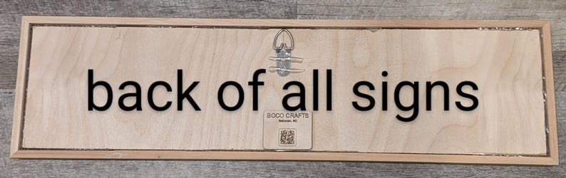 This is the back of all the signs. All natural wood with a hanger in the center and our tag with our name, BOCO CRAFT, where we live, Belhaven, NC and a QR code to our Facebook page.