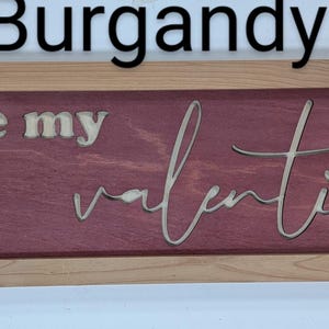 Handmade cypress frame with Baltic birch burgandy background and natural Baltic birch letters reading ...be my Valentine. Be my is in printed letters and the valentine in script. The words are recessed into the wood.