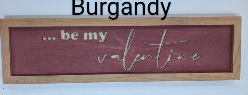 Handmade cypress frame with Baltic birch burgandy background and natural Baltic birch letters reading ...be my Valentine. Be my is in printed letters and the valentine in script. The words are recessed into the wood.