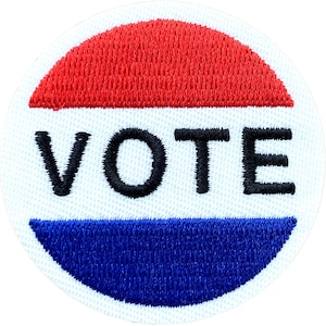 Może przedstawiać: Okrągła, haftowana naszywka w kolorze białym, czerwonym i niebieskim z napisem "VOTE" czarnymi literami.