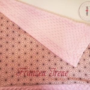 May include: Pink and white baby blanket with a geometric pattern and the name "Franzen Irene" embroidered in red.