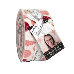 May include: A rolled fabric bundle featuring a repeating leaf pattern in shades of pink, red, and beige on a white background. The bundle is tied with a ribbon and a tag with the text "moda FABRICS + SUPPLIES".