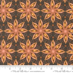 May include: Close-up of a fabric with a repeating floral pattern. The flowers are in shades of peach, orange, and yellow, set against a dark brown background. The design includes small dots and geometric shapes. A ruler is at the bottom.