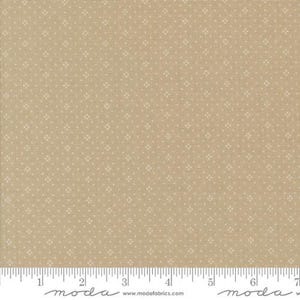 May include: Tan fabric with a small white floral pattern. The fabric has a ruler along the bottom edge with measurements in inches. The fabric is likely used for quilting or other sewing projects.