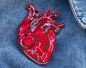 May include: Red embroidered anatomical heart patch. The patch is detailed with veins and arteries.