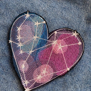 May include: A heart-shaped embroidered patch with a constellation design. The patch is a dark purple and pink color with white stitching and stars.