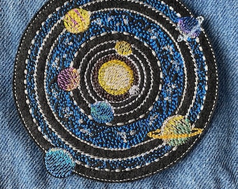 May include: Embroidered patch depicting a black and blue solar system with a yellow sun and multiple planets in orbit. The patch is circular and has a white outline.
