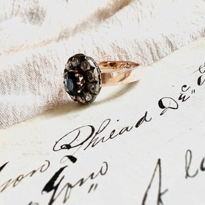 May include: A vintage ring with a black gemstone surrounded by a halo of small diamonds set in a gold band.