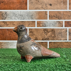 Peut inclure: Une figurine d'oiseau en céramique peinte à la main avec des accents bruns, gris et rouges. L'oiseau est perché sur une surface d'herbe artificielle verte.