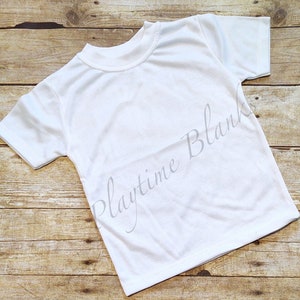 May include: White short-sleeved t-shirt with a crew neck. The shirt is laying flat on a wooden surface. The text "Playtime Blank" is printed in gray on the shirt.
