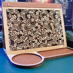 May include: A wooden phone stand with a cutout design of butterflies and flowers. The stand has two circular trays on the bottom.