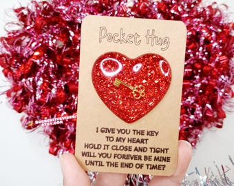 May include: A brown card with the text "Pocket Hug" and a red glitter heart with a gold key inside. The card reads "I give you the key to my heart. Hold it close and tight. Will you forever be mine until the end of time?"
