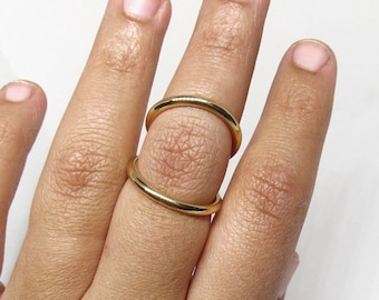 May include: A gold double ring worn on a finger. The ring is made of two thin bands of metal that are connected together.