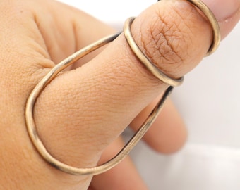 May include: A gold thumb ring with a unique design. The ring is made of two bands that are intertwined and form a loop around the thumb.