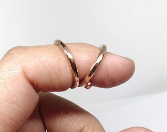 May include: Two thin, gold-colored rings worn on a finger.