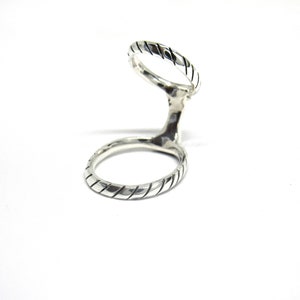 May include: A silver double ring with a twisted design. The ring is open on one side and has two bands that are connected.