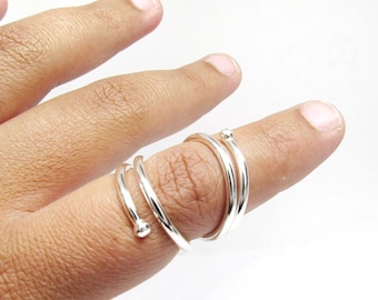 May include: A silver spiral ring with two small balls at the ends. The ring is worn on a finger.
