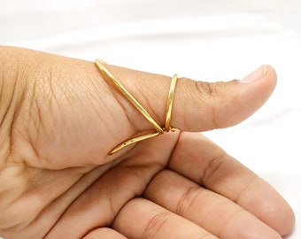 May include: A gold thumb ring with a unique, twisted design. The ring is made of a single piece of metal that is bent and twisted to create a unique shape.