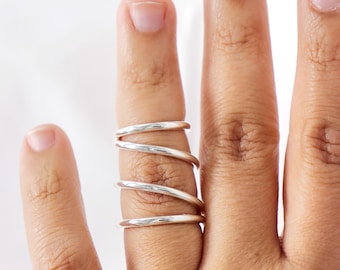 May include: A silver ring with multiple bands wrapped around the finger.