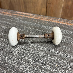 Puede incluir: Pomo de puerta antiguo con manijas ovaladas de cerámica blanca y una varilla de metal oxidado. La ferretería de la puerta está diseñada para instalarse en una puerta. El pomo de la puerta es de estilo vintage.