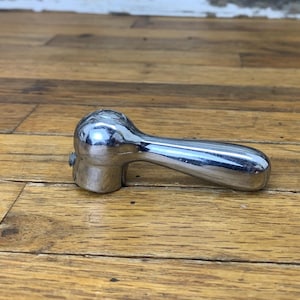 May include: A chrome-plated metal handle with a rounded knob and a long, slender handle. The handle is designed for use with a door or other object.