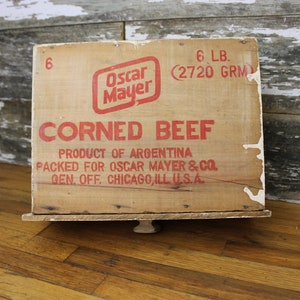 May include: Vintage wooden crate for corned beef, labeled "Oscar Mayer" with the text "6 LB. (2720 GRM) CORNED BEEF PRODUCT OF ARGENTINA PACKED FOR OSCAR MAYER & CO. GEN. OFF. CHICAGO, ILL U.S.A."