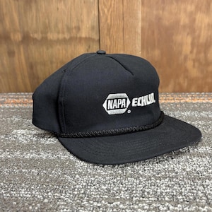 May include: Black snapback hat with a flat brim and a black rope detail. The hat features the white text "NAPA ECHLIN" in a stylized font on the front. The hat is made of a durable fabric and has a classic, casual style.