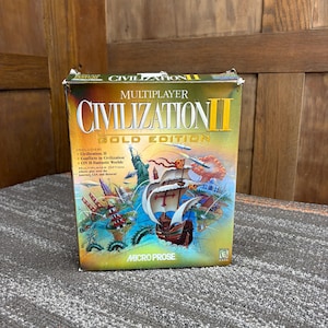 May include: A Civilization II Gold Edition video game box. The box features a colorful illustration of a ship, landmarks, and the text "Civilization II Gold Edition." The Micro Prose logo is visible at the bottom.