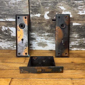 Puede incluir: Tres piezas de herrajes de puerta antiguos en acabado cobre desgastado. El juego incluye dos placas de puerta y una cerradura de puerta.