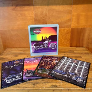 May include: A Harley-Davidson three-ring binder featuring a motorcycle silhouette against a sunset, accompanied by four matching folders displaying various motorcycle models, flame patterns, and the Harley-Davidson logo with text.