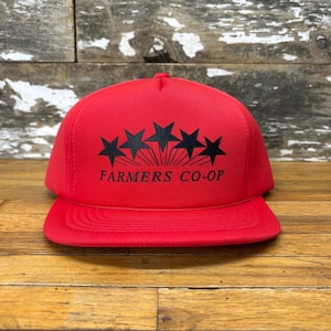 May include: A red trucker hat with a black five-pointed star design and the text "FARMERS CO-OP" in black.