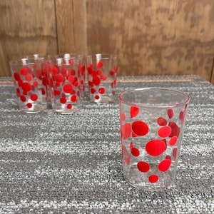 Puede incluir: Juego de seis vasos transparentes con un patrón de lunares rojos. Los vasos son cilíndricos y tienen un diseño sencillo y clásico. Los puntos rojos varían en tamaño y están distribuidos uniformemente.