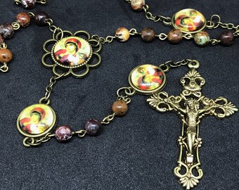 Könnte beinhalten: Eine braune und goldene Rosenkranz mit einem Kruzifix und runden Perlen mit religiösen Bildern. Die Perlen sind aus Stein und das Metall ist antikes Gold.