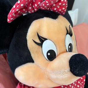 This oversized Minnie Mouse plush from the early 90s features authentic Disney detailing, from her embroidered eyes to her classic dress. A rare find for collectors of vintage Disney merchandise.