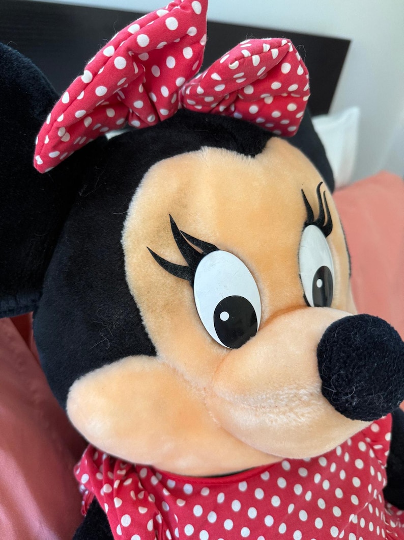 This oversized Minnie Mouse plush from the early 90s features authentic Disney detailing, from her embroidered eyes to her classic dress. A rare find for collectors of vintage Disney merchandise.
