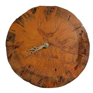 May include: A round, brown clock with a deer design carved into the face. The clock has black numbers and silver hands. The clock face appears to be made from a cross-section of a tree trunk.
