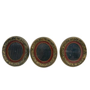 May include: Three antique, round frames with a dark center and a red inner circle. The frames have a gold-colored, ornate design around the edges. The frames are displayed against a white background.