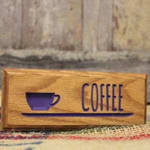 May include: A wooden sign with the word "COFFEE" carved in purple lettering. A purple coffee cup icon is to the left of the word "COFFEE".