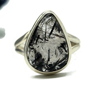 May include: A silver ring featuring a teardrop-shaped black and clear quartz stone.