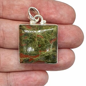 May include: A silver pendant with a square green and red jasper stone. The stone has a swirling pattern of red and green.