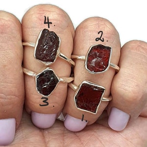 Puede incluir: Cuatro anillos de plata con engastes de piedras preciosas rojas. Los anillos están numerados del 1 al 4.