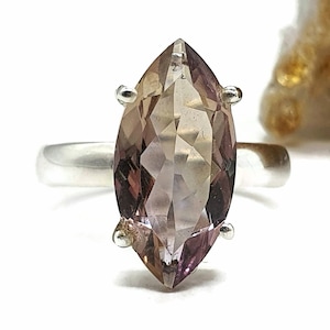 May include: A silver ring with a large, faceted, marquise-shaped amethyst gemstone. The gemstone is a light purple color with a hint of brown.