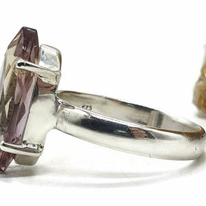 May include: A silver ring with a large, faceted, purple gemstone. The ring is set in a simple band.