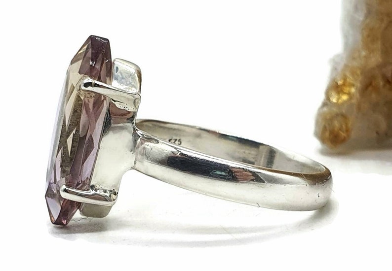 May include: A silver ring with a large, faceted, purple gemstone. The ring is set in a simple band.