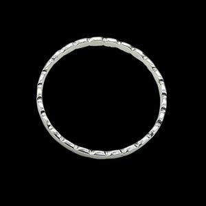 Puede incluir: Un anillo plateado con un patr&oacute;n repetitivo de peque&ntilde;as hendiduras curvas alrededor de la banda. El anillo est&aacute; sobre un fondo negro, resaltando su brillo met&aacute;lico y su intrincado dise&ntilde;o. El dise&ntilde;o del anillo es simple pero elegante.