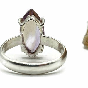 May include: A silver ring with a marquise-shaped amethyst gemstone. The ring is set in a simple band.