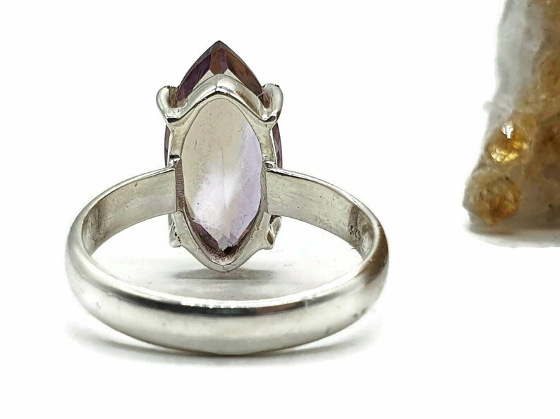 May include: A silver ring with a marquise-shaped amethyst gemstone. The ring is set in a simple band.