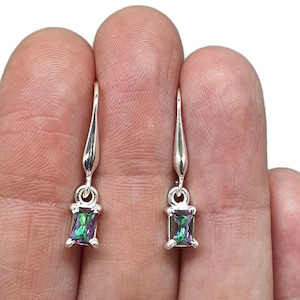 May include: A pair of silver drop earrings. Each earring has a rectangular, iridescent gemstone in green, purple, and blue. The earrings hang from a slender, curved hook.