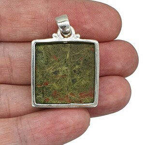 May include: A silver pendant with a square green and red jasper stone.